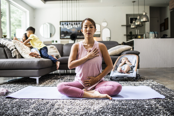 Mother doing yoga at home surrounded by children